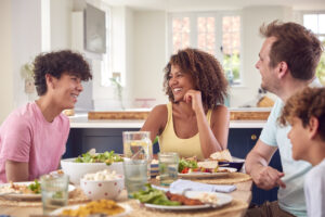 Family Sitting Around Table At Home Eating Meal Together