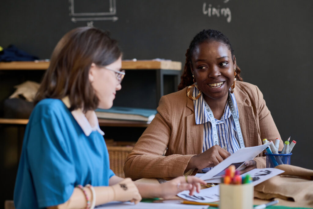 Portrait of woman talking to student during sewing class