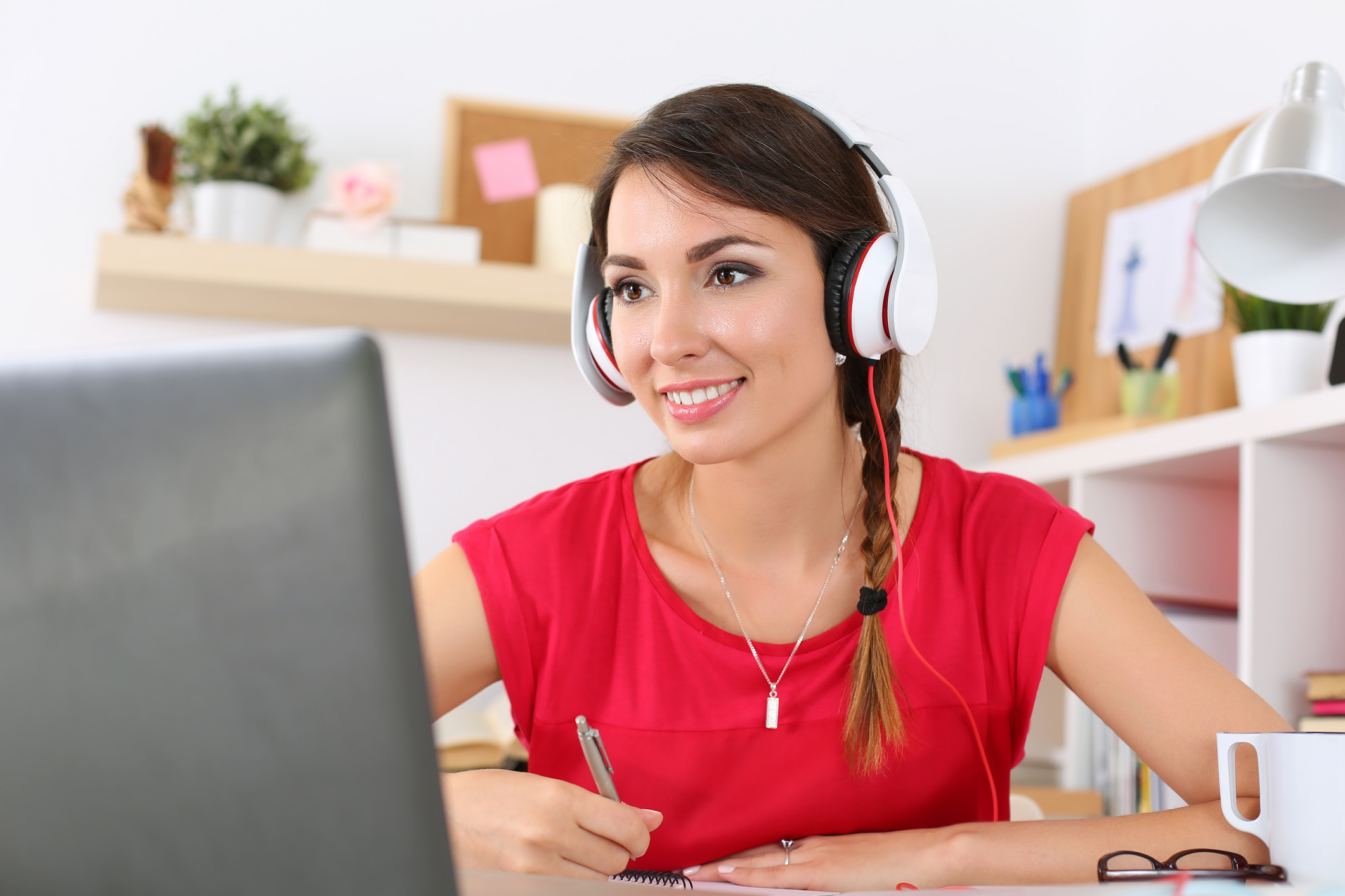 Young woman looking in laptop display watching training course and listening it with headphones.